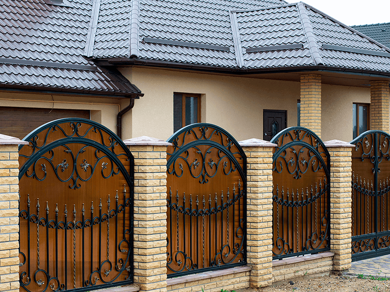 Забор из кованых секций с кирпичными столбами